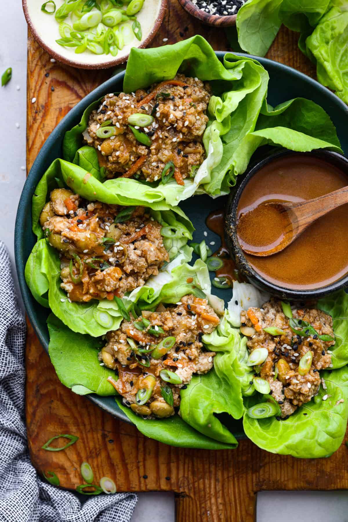 Overhead shot of asian lettuce wraps on plate with bowl of sauce. 