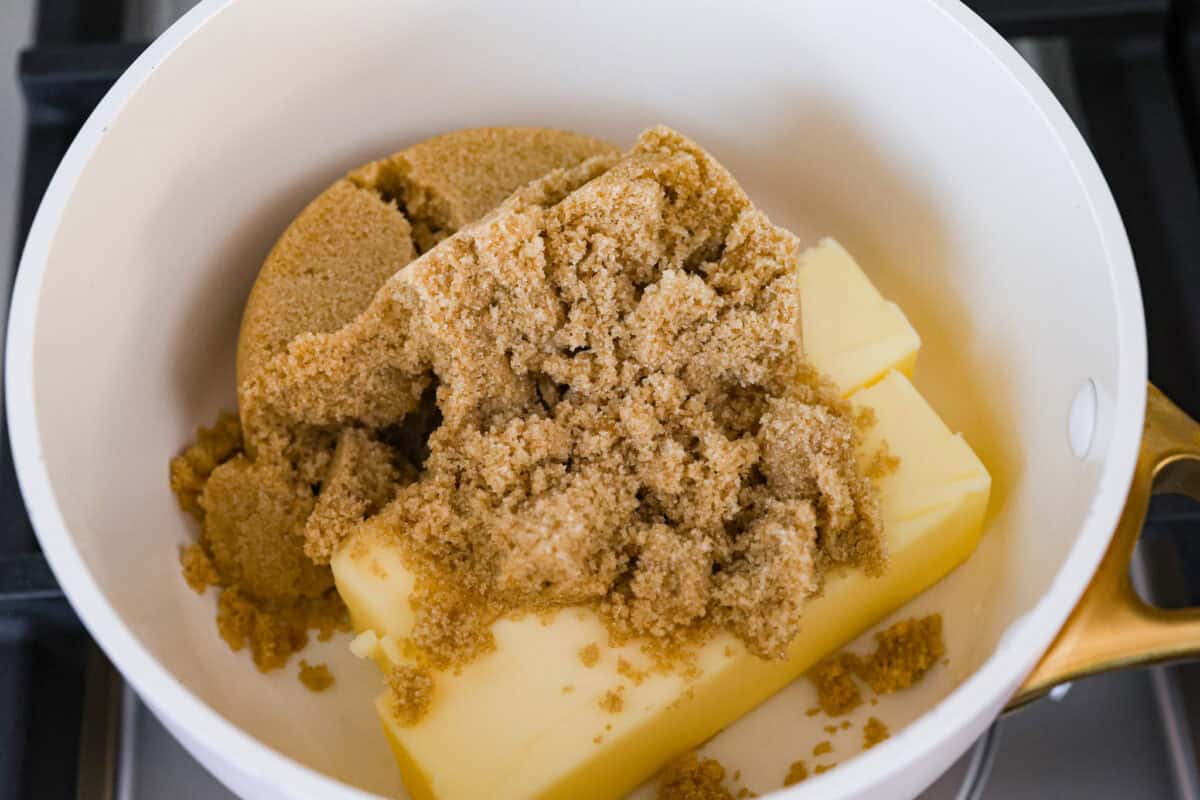 Overhead shot of a bowl with two sticks of butter covered with a pile of brown sugar.