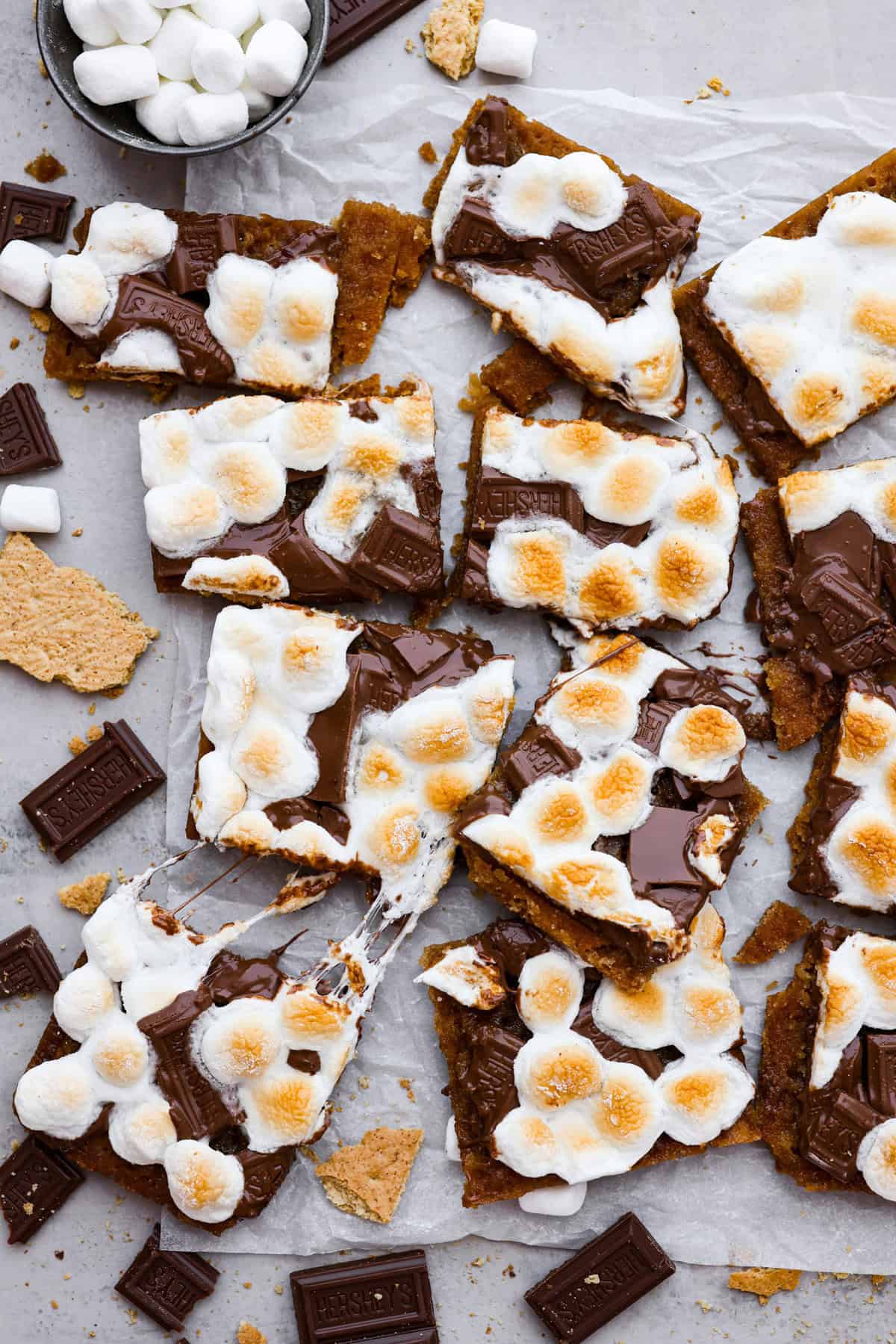 S'mores crack is a quick way to enjoy the classic s'more experience without a campfire. Featuring a buttery graham cracker crust, rich melted chocolate, and toasted marshmallows, this treat will quickly become a family favorite. Overhead shot of cut up pieces of S'mores crack.