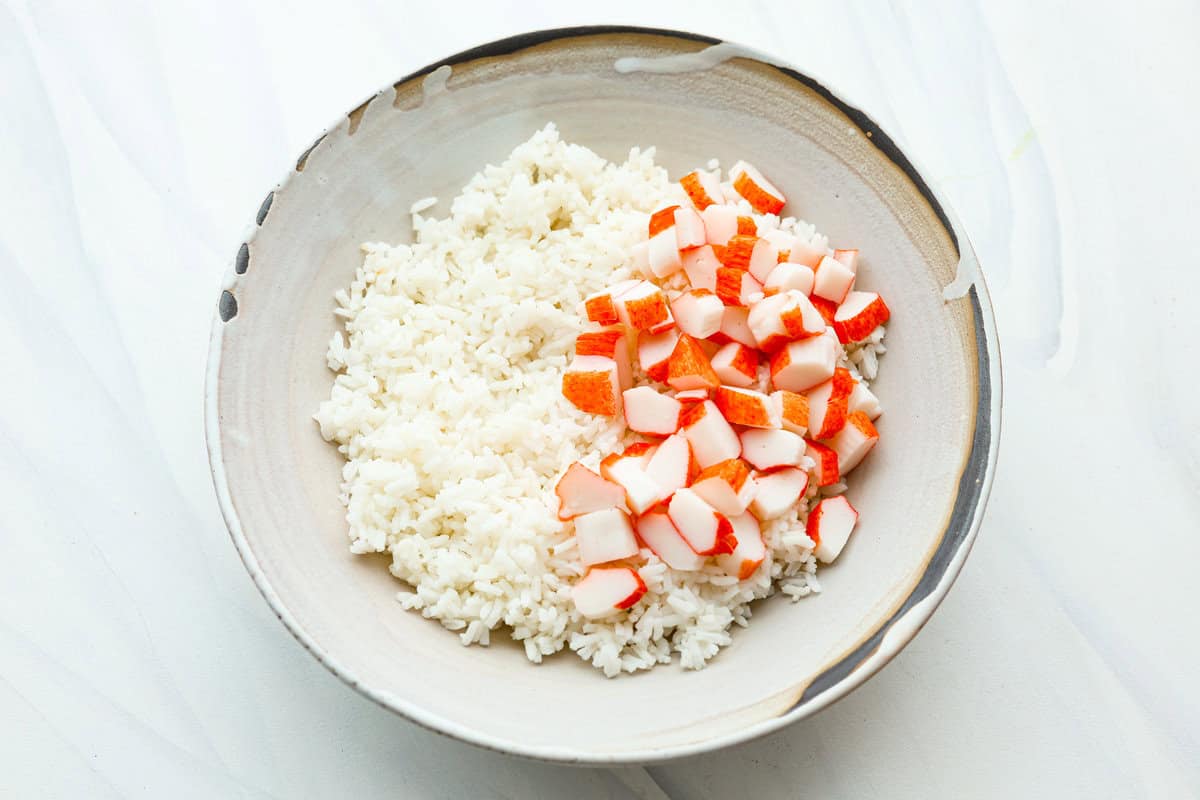 This sushi bowl is a deconstructed California sushi roll loaded with irresistible flavor and all of the best sushi ingredients. It’s layered with sushi rice, crab, cucumber, avocado, a tasty sauce, and more. It’s easy to make and ready to serve in just 20 minutes! Overhead shot of bowl with rice and imitation crab.