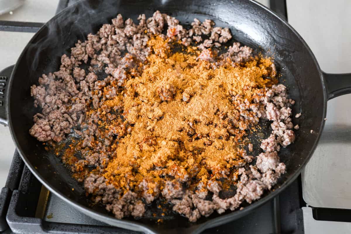 Overhead shot of ground beef being cooked in a skillet with taco seasoning. 