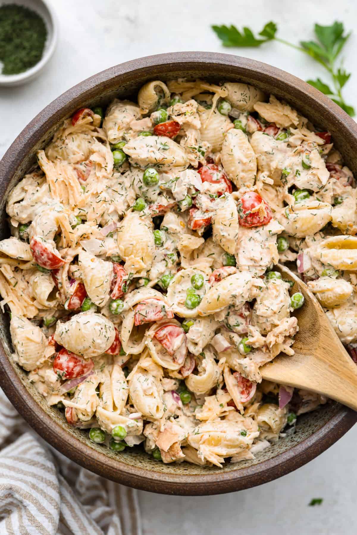 Top view of tuna pasta salad in a bowl with a wood spoon.