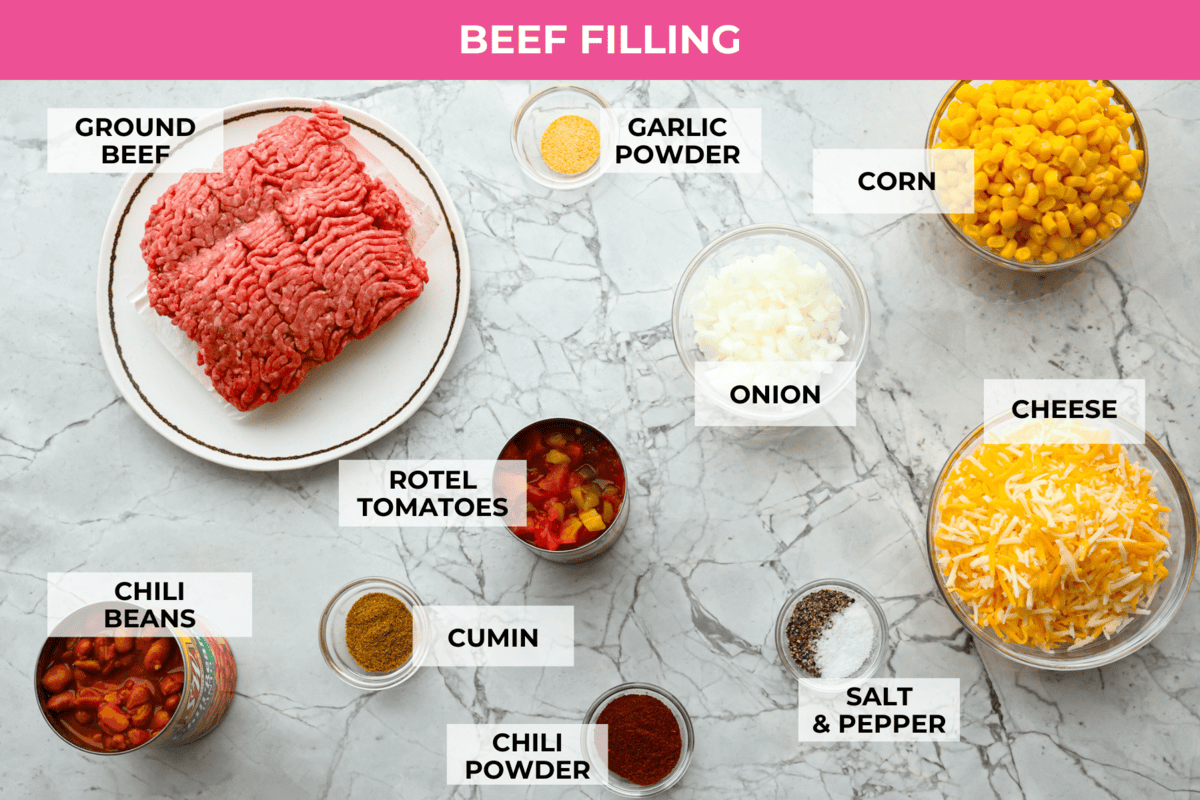 Cowboy Cornbread Casserole is a flavorful, comforting meal that's so easy to make. Seasoned ground beef, corn, pinto beans, and Rotel tomatoes are layered with shredded cheddar cheese and a cornbread topping for a winning dinner! Overhead shot of labeled beef filling ingredients.