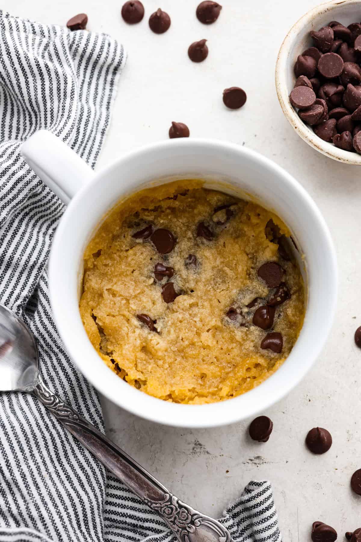 This cookie in a mug recipe is the perfect way to satisfy your cookie craving. In just a few minutes, you can enjoy a warm, buttery, ooey-gooey cookie right in your own mug. Top it with a scoop of ice cream or a dollop of whipped cream, and you'll find yourself in cookie heaven! Overhead shot of cooked cookie in a mug.