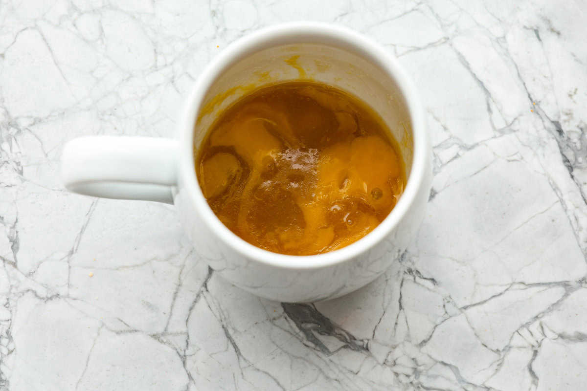 This cookie in a mug recipe is the perfect way to satisfy your cookie craving. In just a few minutes, you can enjoy a warm, buttery, ooey-gooey cookie right in your own mug. Top it with a scoop of ice cream or a dollop of whipped cream, and you'll find yourself in cookie heaven! Overhead shot of sugars, egg yolk and butter mixed in a mug.