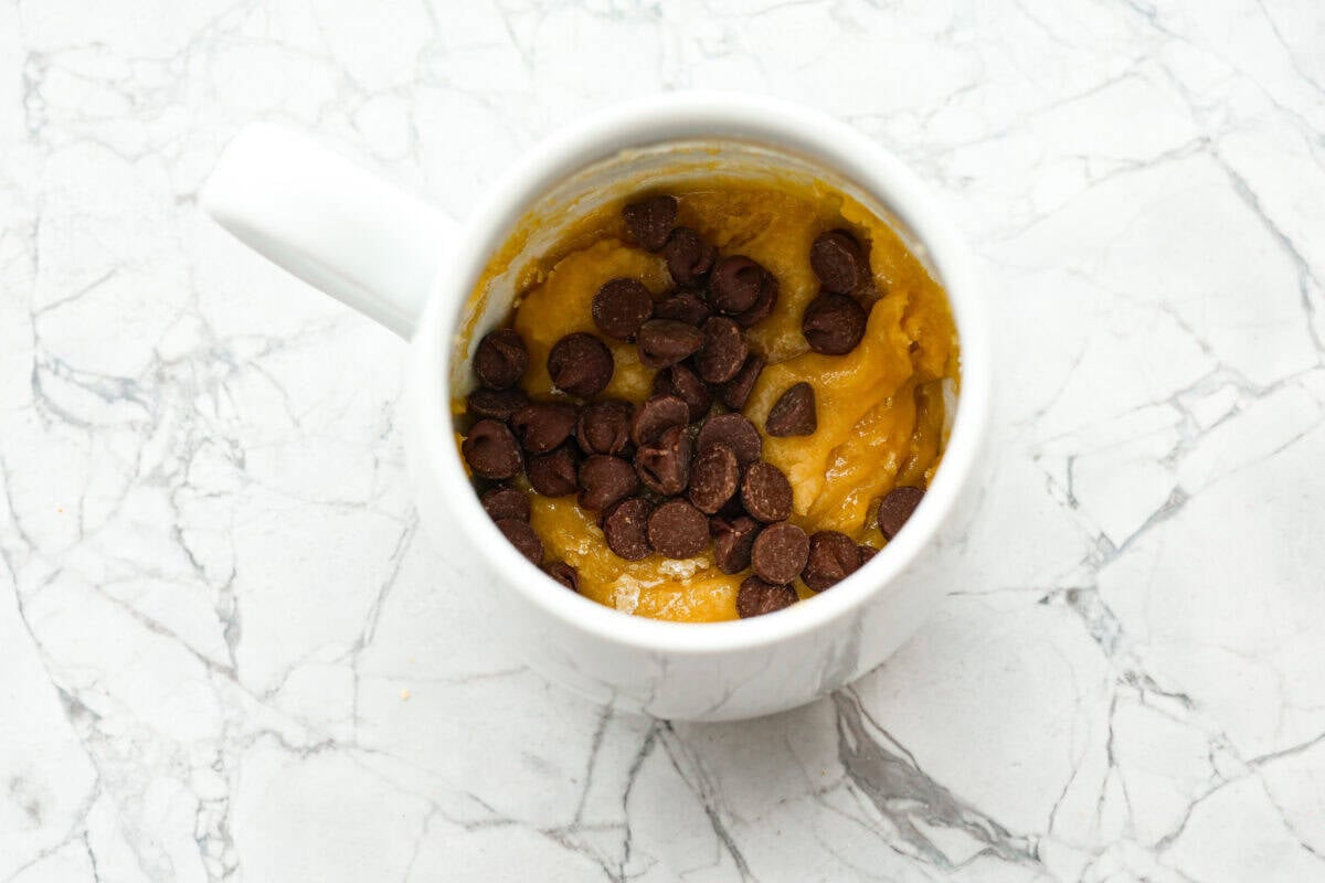 Overhead shot of mug with cookie dough and chocolate chips dded. 