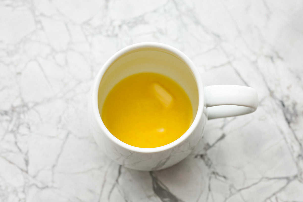 This cookie in a mug recipe is the perfect way to satisfy your cookie craving. In just a few minutes, you can enjoy a warm, buttery, ooey-gooey cookie right in your own mug. Top it with a scoop of ice cream or a dollop of whipped cream, and you'll find yourself in cookie heaven! Overhead shot of butter melted in a mug.