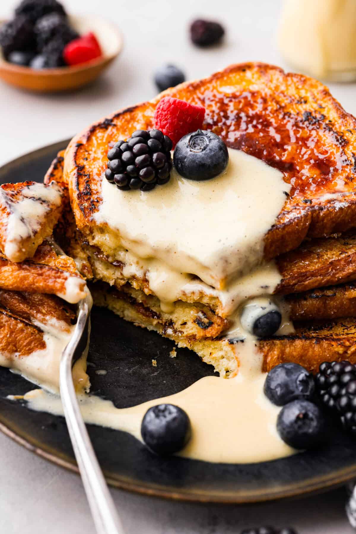 Close view of a fork cutting into the stacked creme brûlée French toast.