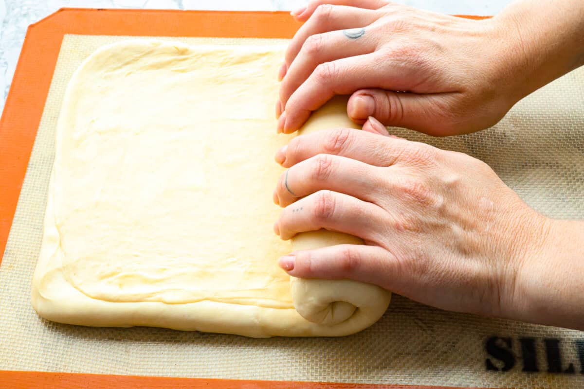 Overhead shot of someone rolling up dough. 