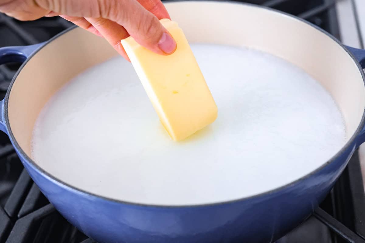 This is the BEST recipe for how to boil corn on the cob! Fresh summer corn gets boiled in a sweet creamy mixture of milk, butter, sugar, and salt. Cook and flavor your corn all in one pot! Third photo of the butter adding to the pot.