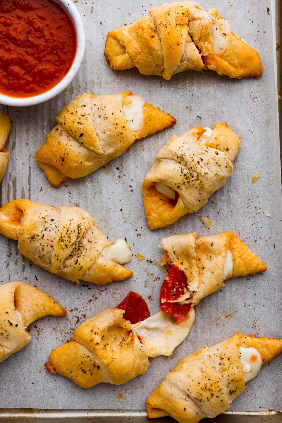 Overhead shot of a pan of pizza stuffed crescent rolls with gooey cheese melting out of the edges. 