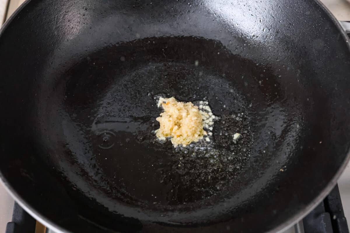 Overhead shot of oil and minced garlic in a skillet. 