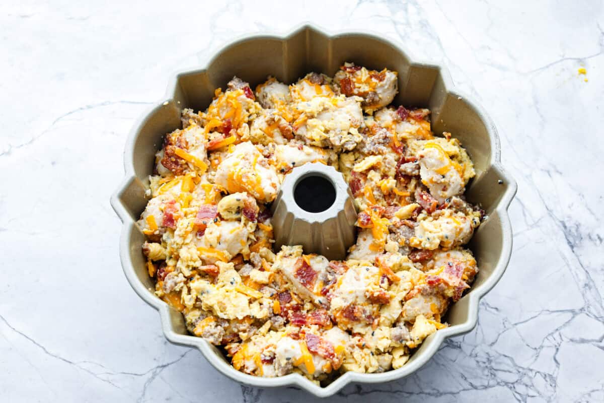 Overhead shot of egg, cheese, meat and biscuit mixture in a bundt pan. 