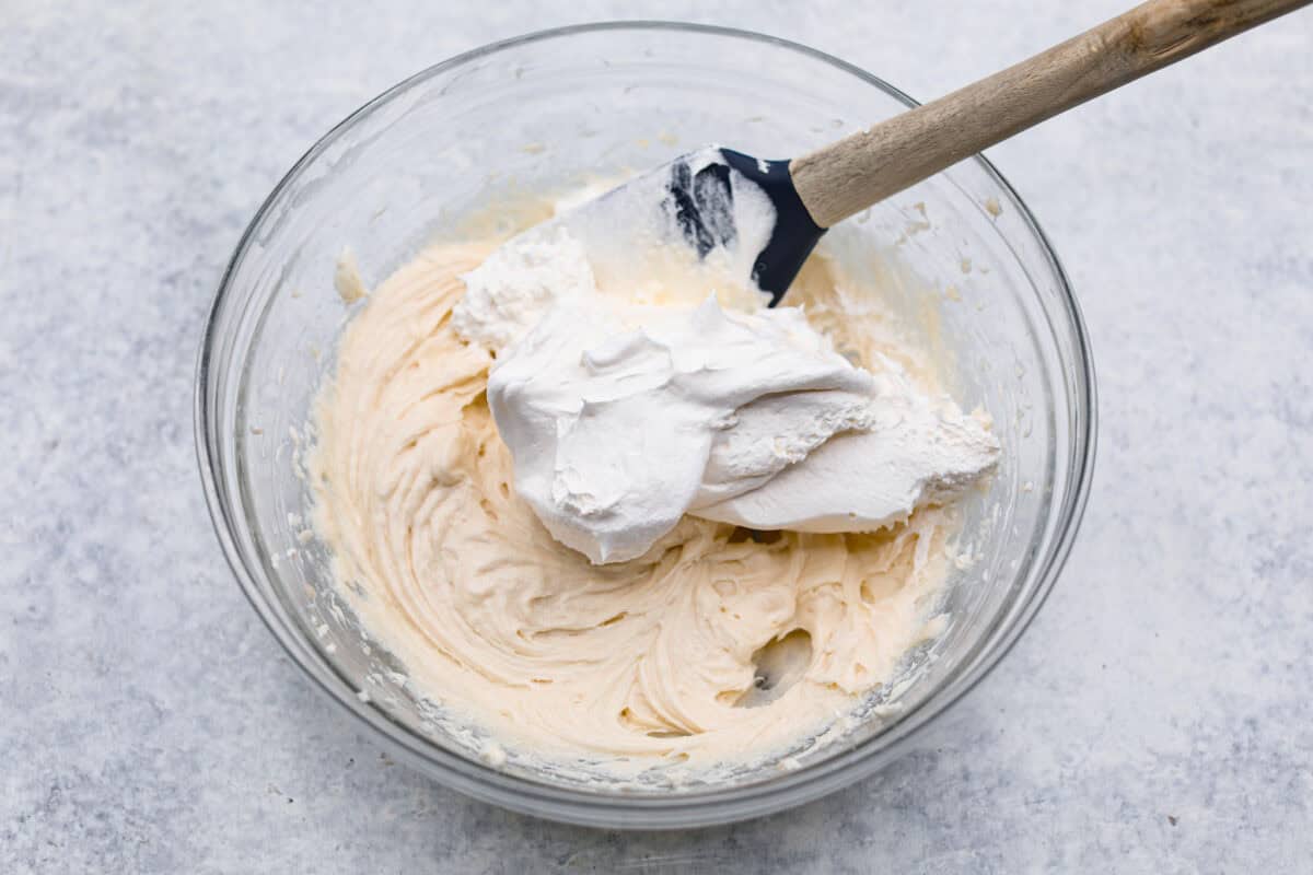 Overhead shot of whipped topping being folded in to the fresh peach pie cream cheese filling. 