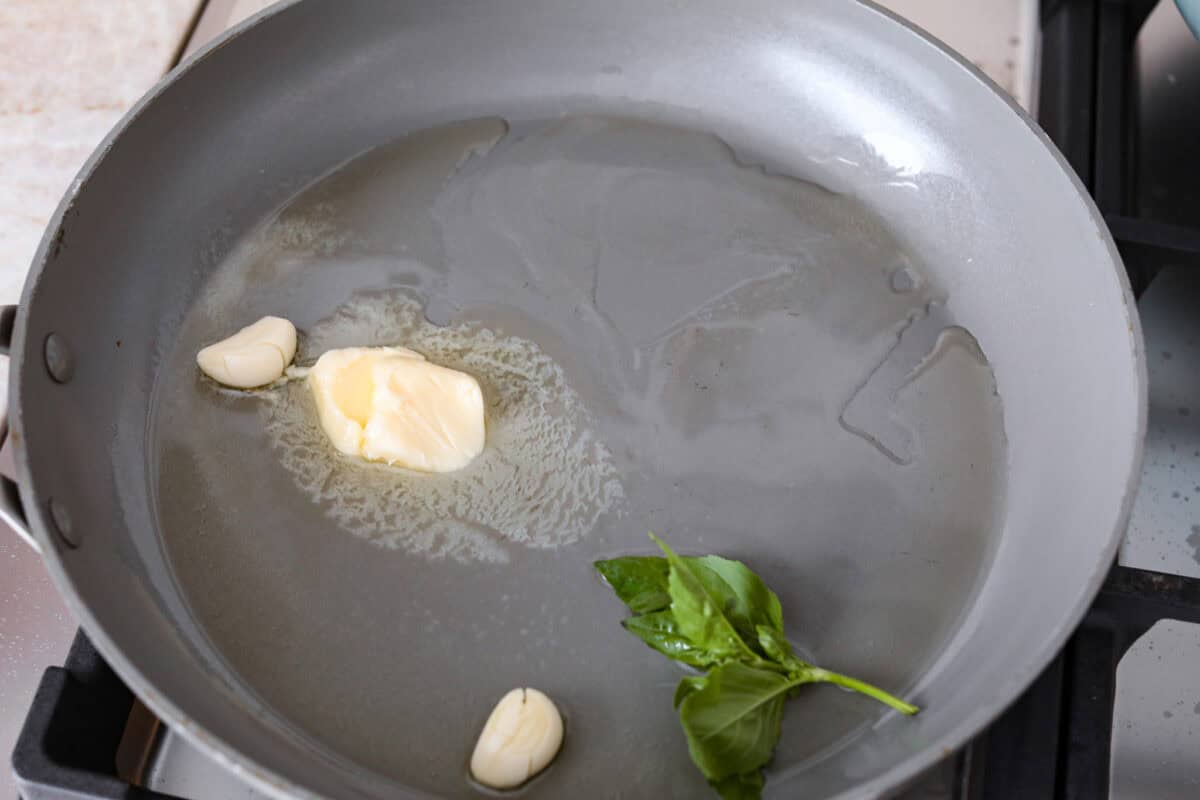 Third photo of the garlic, butter, oil, and basil added to a hot skillet.