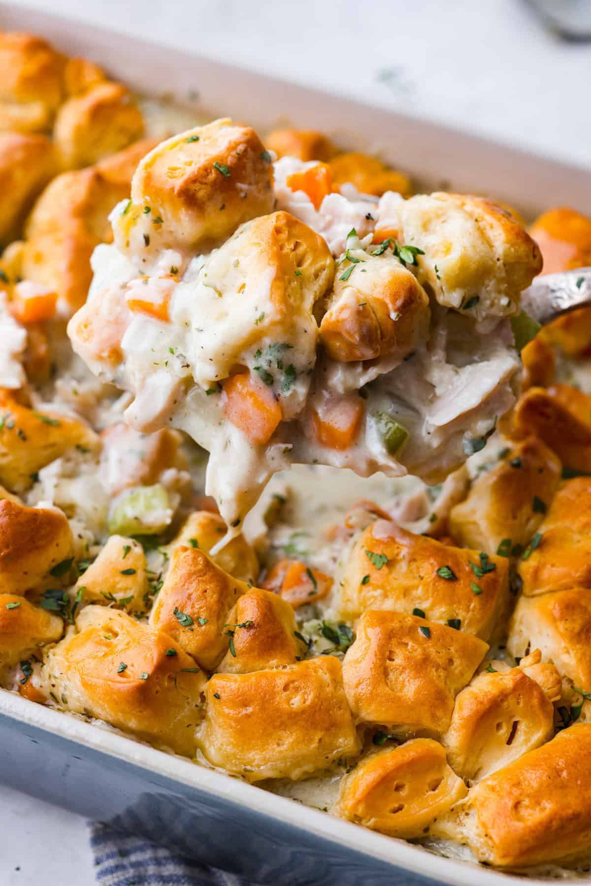 Chicken pot pie casserole is a fun twist on the classic pot pie. It's made with buttery biscuit dough, tender chicken, crunchy veggies, and the most delicious creamy sauce loaded with incredible seasoning. Comfort food at its finest! Close up shot of a scoop of chicken pot pie casserole.