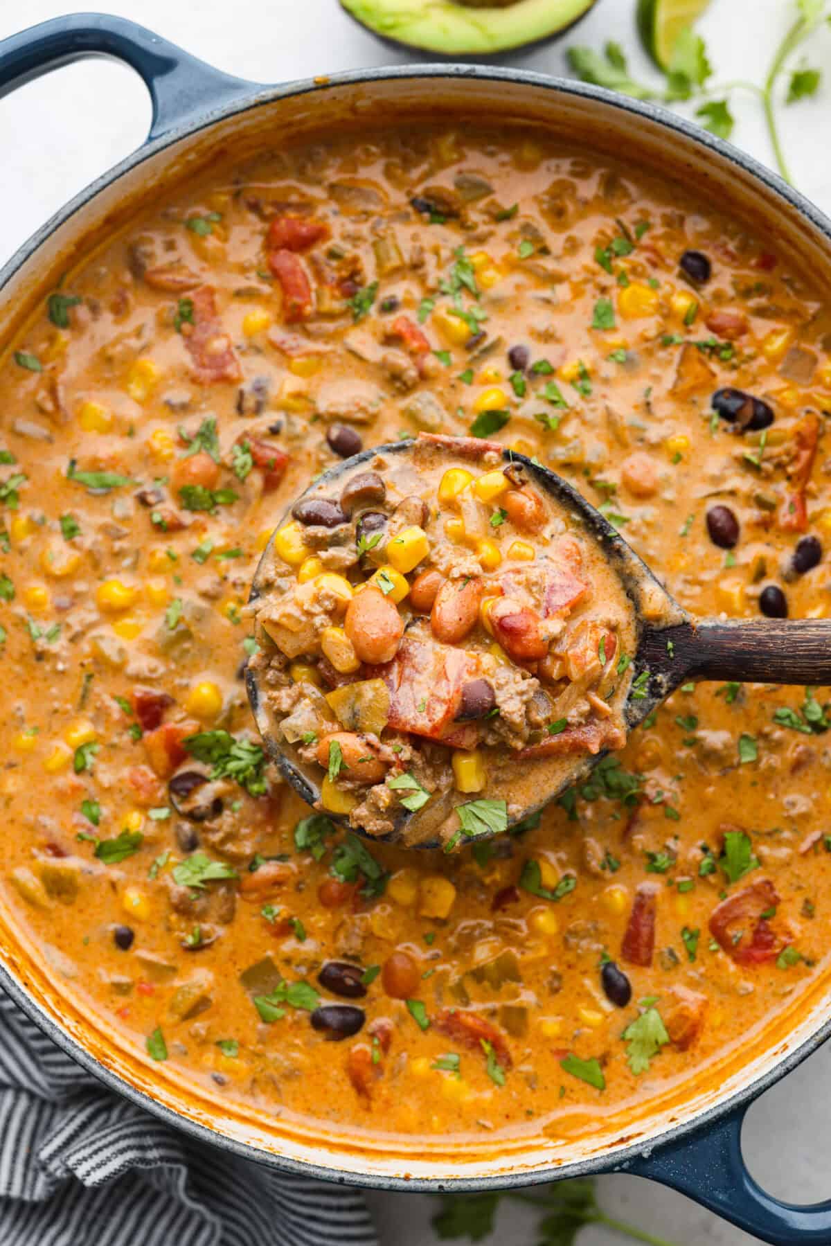 Overhead shot of a pot of creamy taco soup with a wooden spoon ladling out a scoop.