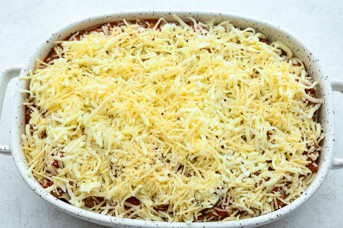 Million Dollar Ravioli Casserole is a flavorful casserole version of the classic! It's easy to make with mouthwatering layers of cheesy ravioli, meat sauce, and melted mozzarella cheese on top. This is a comforting, family-friendly dinner that you'll be craving on repeat! Overhead shot of the ravioli and cheese with meat and sauce mixture topped with cheese.