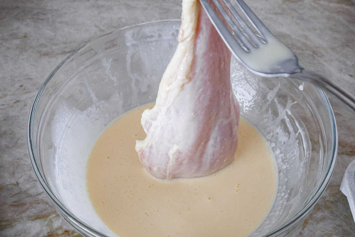 Smothered chicken is a flavorful comfort food full of rich, creamy gravy, tender chicken cutlets, and savory mushrooms. Perfect on its own or paired with mashed potatoes, rice or pasta, you're family will definitely want this on the weekly meal plan. Overhead shot of chicken cutlet in cream and egg mixture.