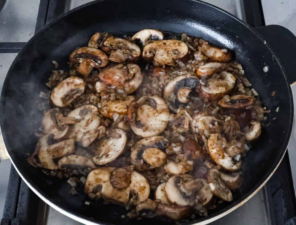 Smothered chicken is a flavorful comfort food full of rich, creamy gravy, tender chicken cutlets, and savory mushrooms. Perfect on its own or paired with mashed potatoes, rice or pasta, you're family will definitely want this on the weekly meal plan. Overhead shot of mushrooms being sautéed in skillet.