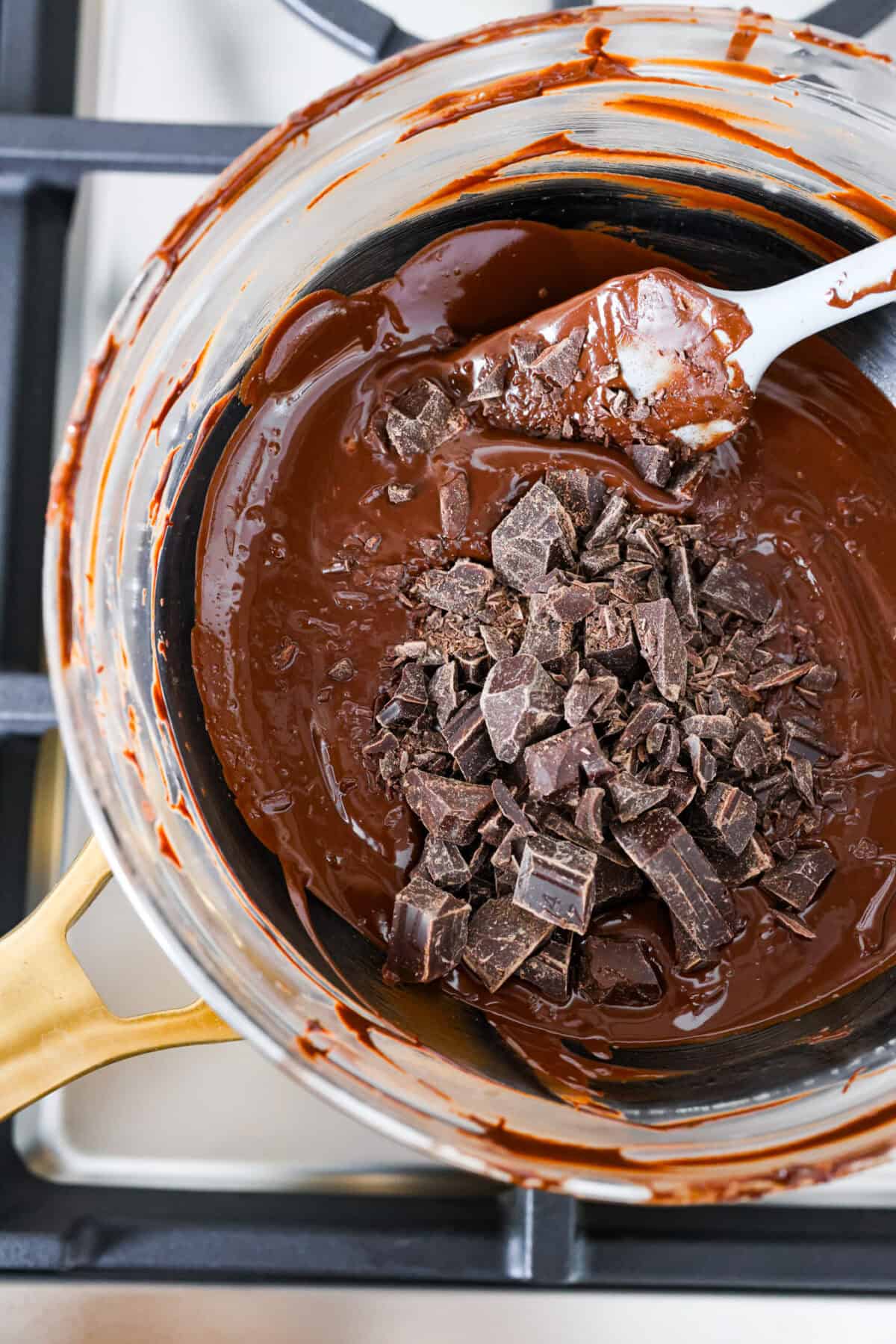 Top close view of melted chocolate in a bowl with chopped chocolate added on top for seeding.