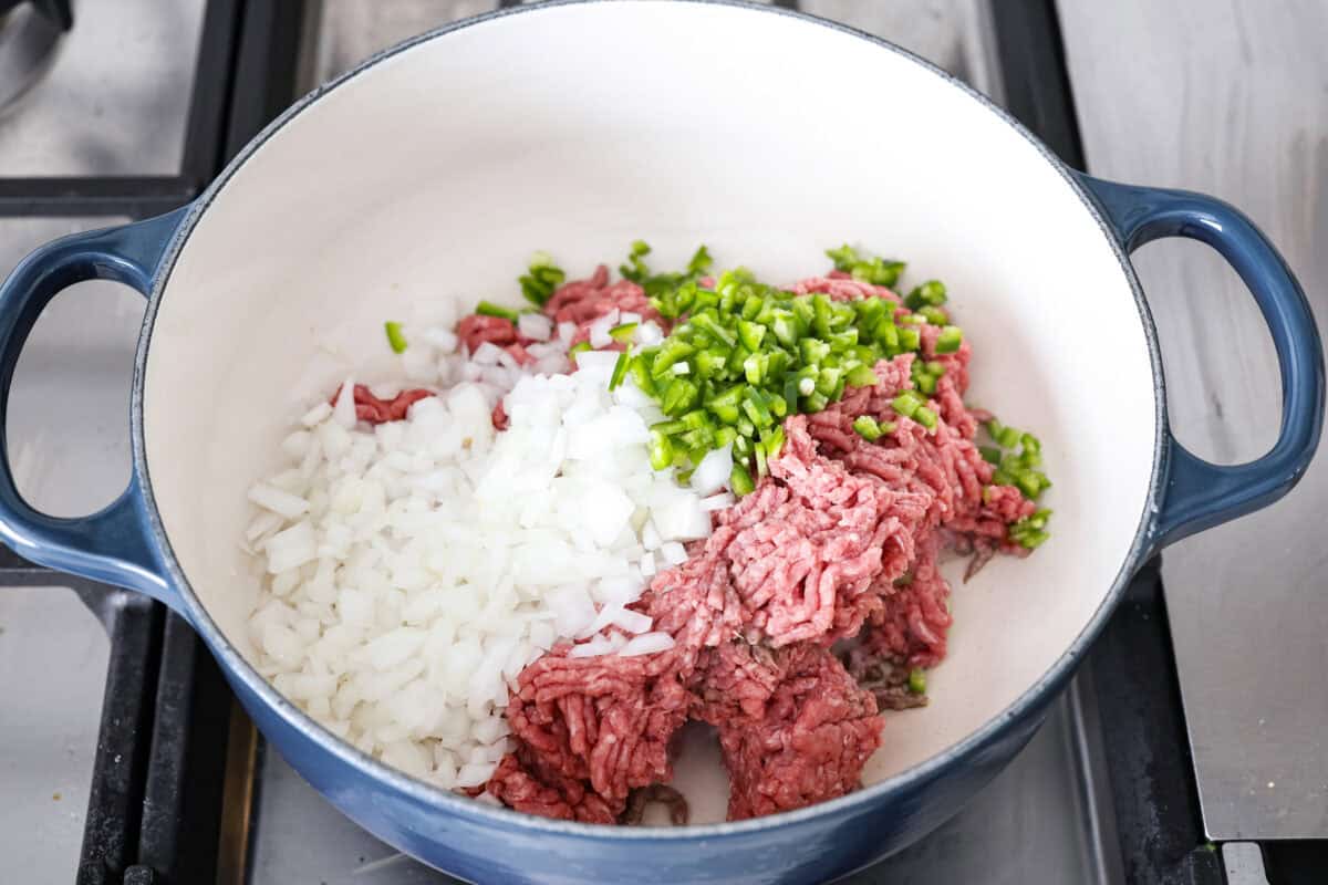 Angle shot of beef, onions and jalapeños in a pot. 