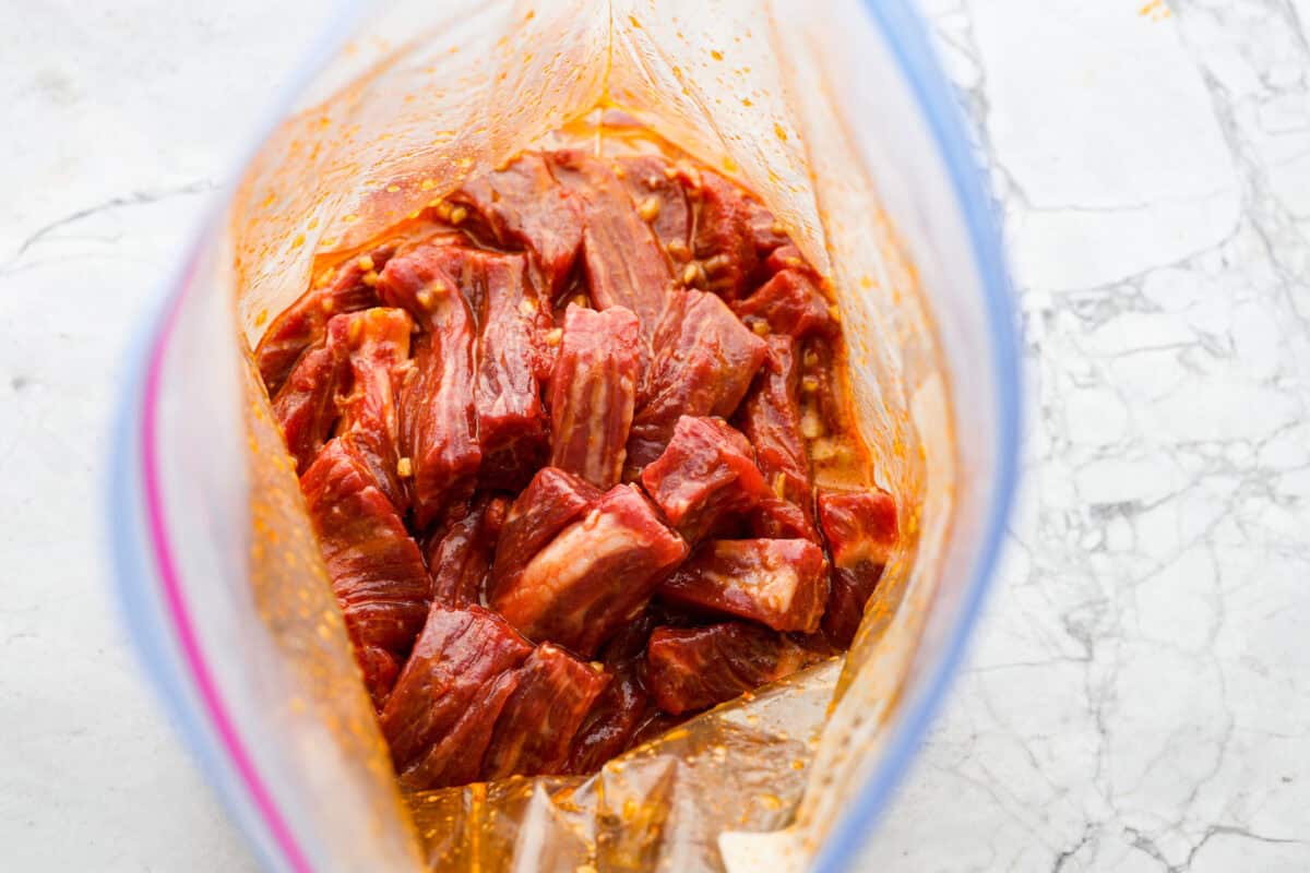 Overhead shot of beef in marinade in a ziplock bag. 