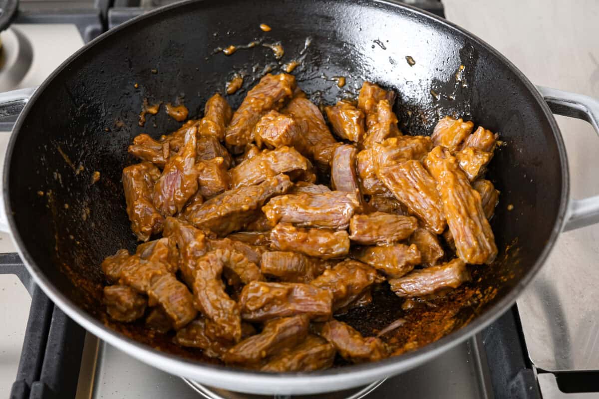 Angle shot of marinated beef cooking in a wok. 