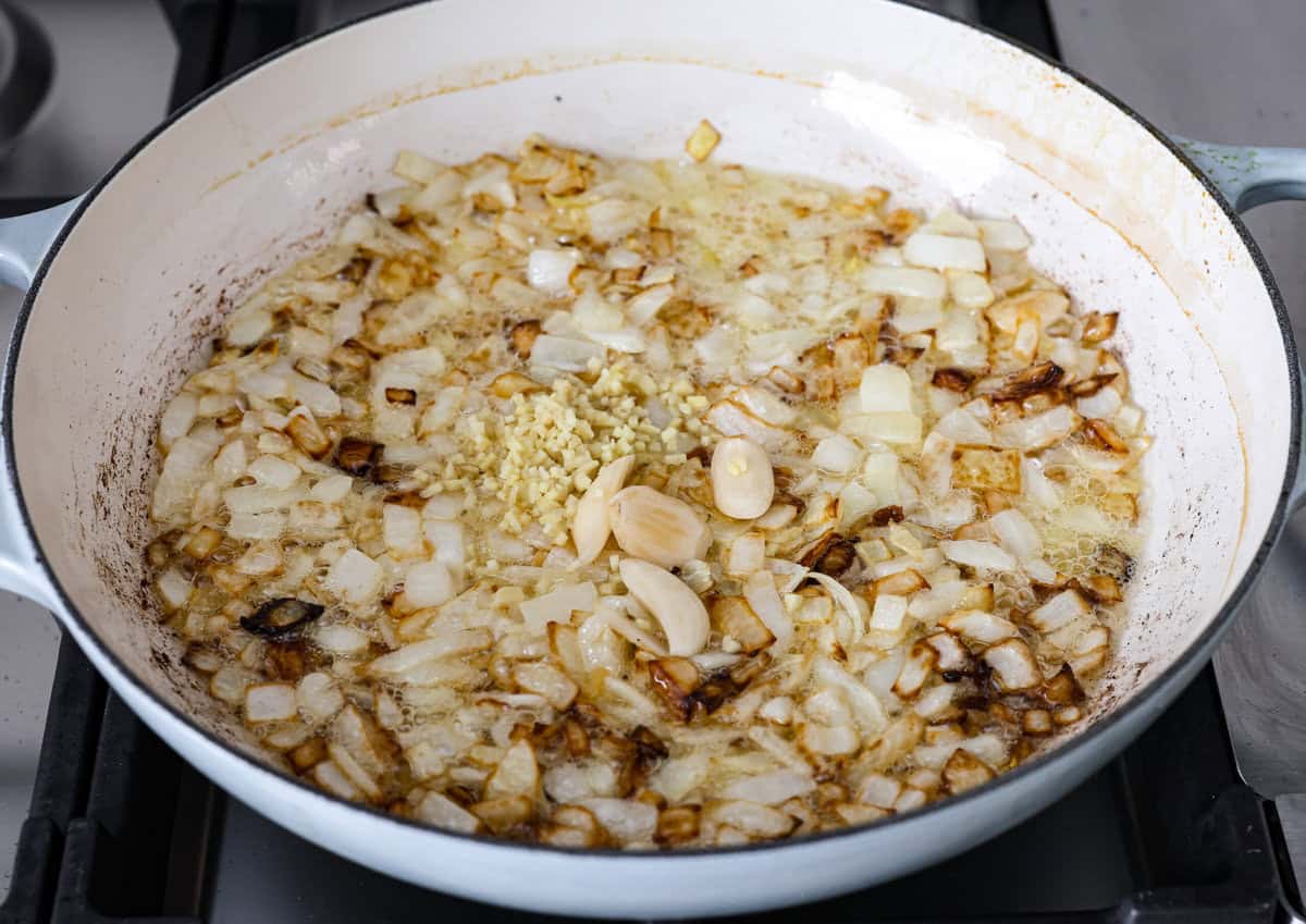 Chicken korma is a traditional Indian chicken dish. It's made with tender chicken smothered in a creamy, wonderfully seasoned sauce. It's so good your family will think you got takeout! Angle shot of onions garlic and ginger being sautéed in the ghee and oil.
