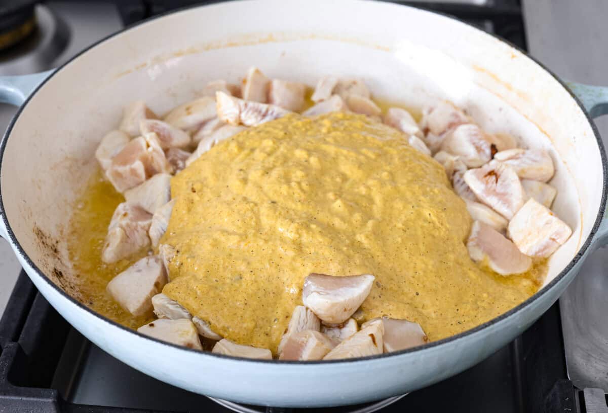 Angle shot of blended sauce over the chicken in the skillet. 