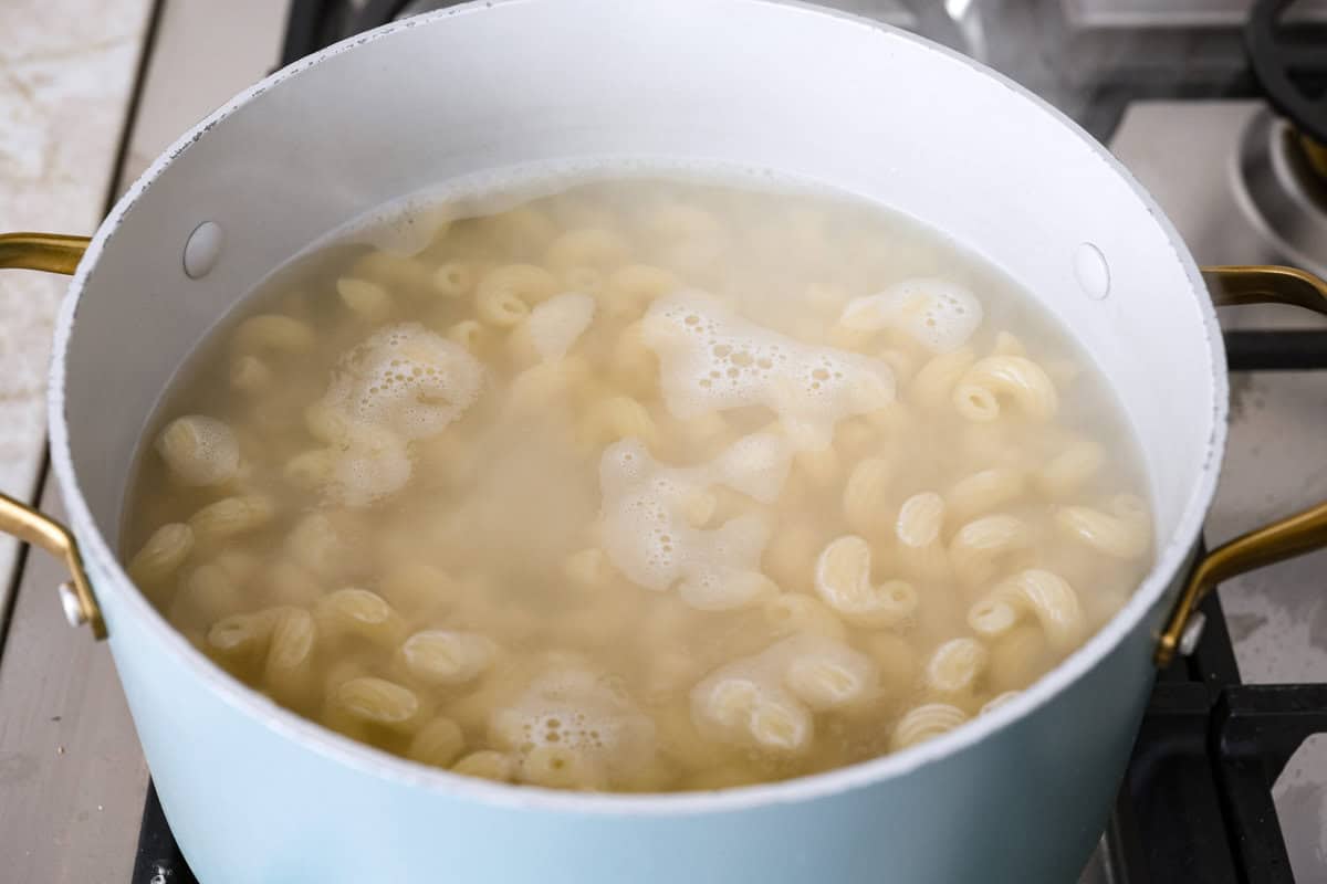 This Boursin pasta recipe has gone viral on social media. It's simple to make and packed with flavor! It's creamy with a distinct zingy bite from the Boursin cheese and sundried tomatoes. This dish screams flavor! It's anything but boring. Angle shot of pasta cooked in boiling water.