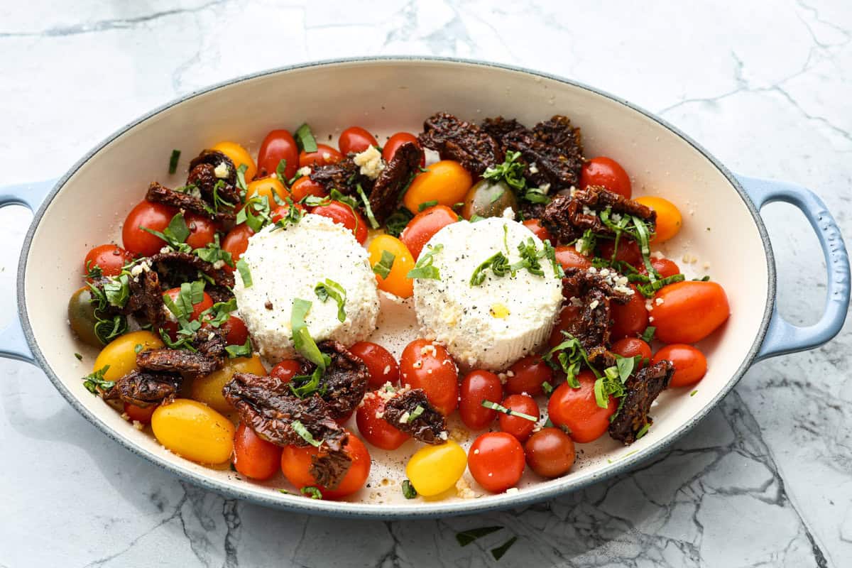 This Boursin pasta recipe has gone viral on social media. It's simple to make and packed with flavor! It's creamy with a distinct zingy bite from the Boursin cheese and sundried tomatoes. This dish screams flavor! It's anything but boring. Angle shot of tomatoes, cheese, onions and sun dried tomatoes in a skillet.