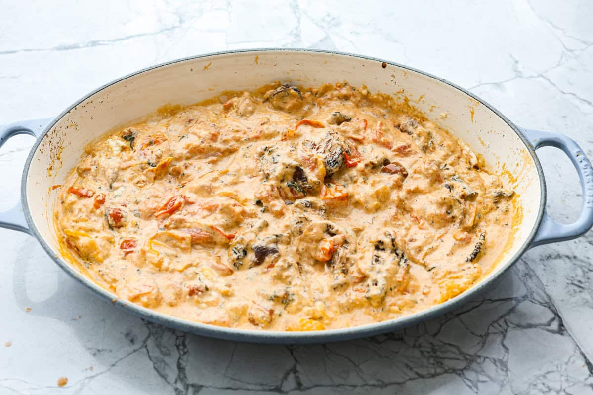 This Boursin pasta recipe has gone viral on social media. It's simple to make and packed with flavor! It's creamy with a distinct zingy bite from the Boursin cheese and sundried tomatoes. This dish screams flavor! It's anything but boring. Angle shot of sauce in a skillet.