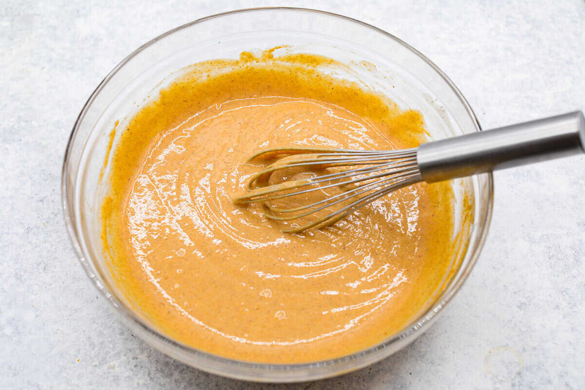 Fall in love with this Pumpkin Delight! A shortbread crust topped with a fluffy cheesecake mixture, a creamy pumpkin layer, and whipped topping. Every bite of this irresistible layered dessert is pumpkin heaven! Fifth photo of the pumpkin layer mixed in a bowl.