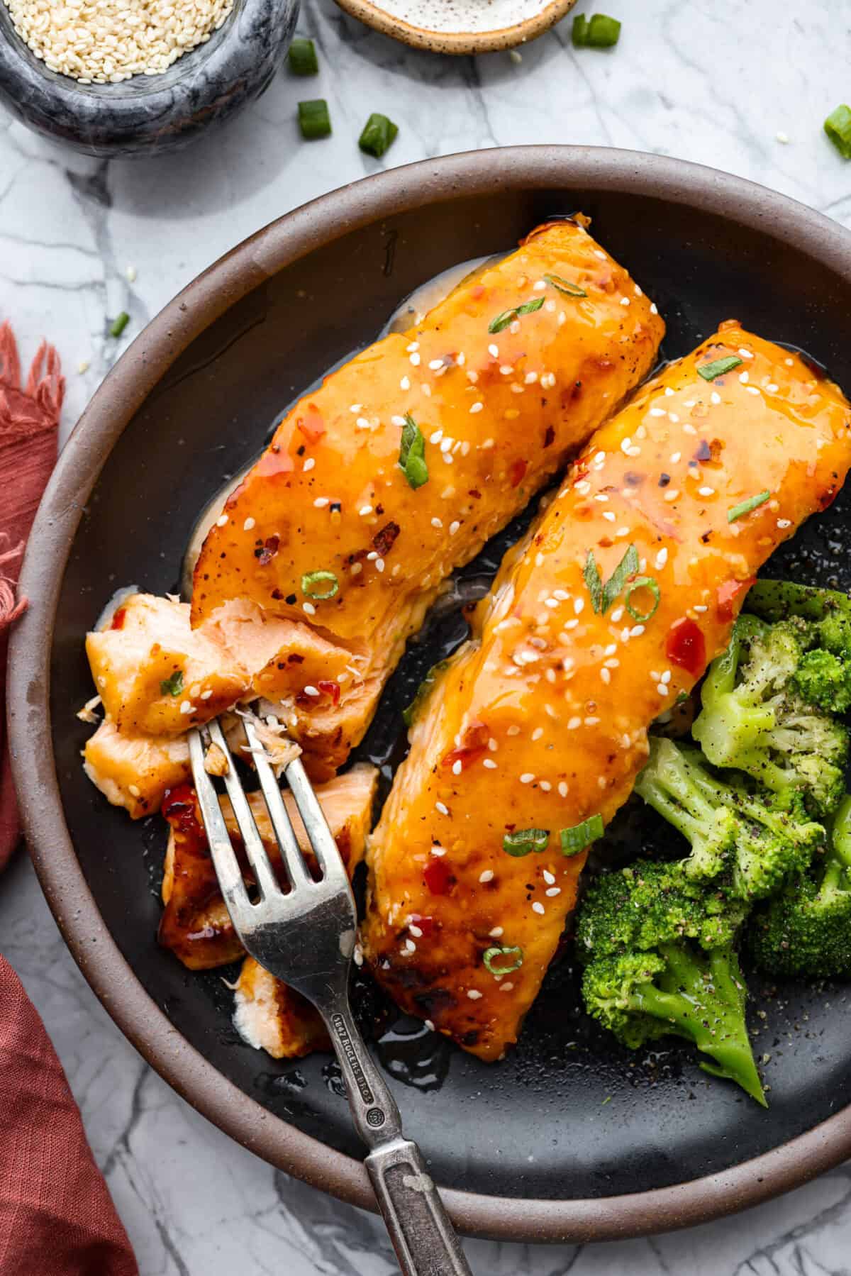 Top shot of bang bang salmon layered next to broccoli. 