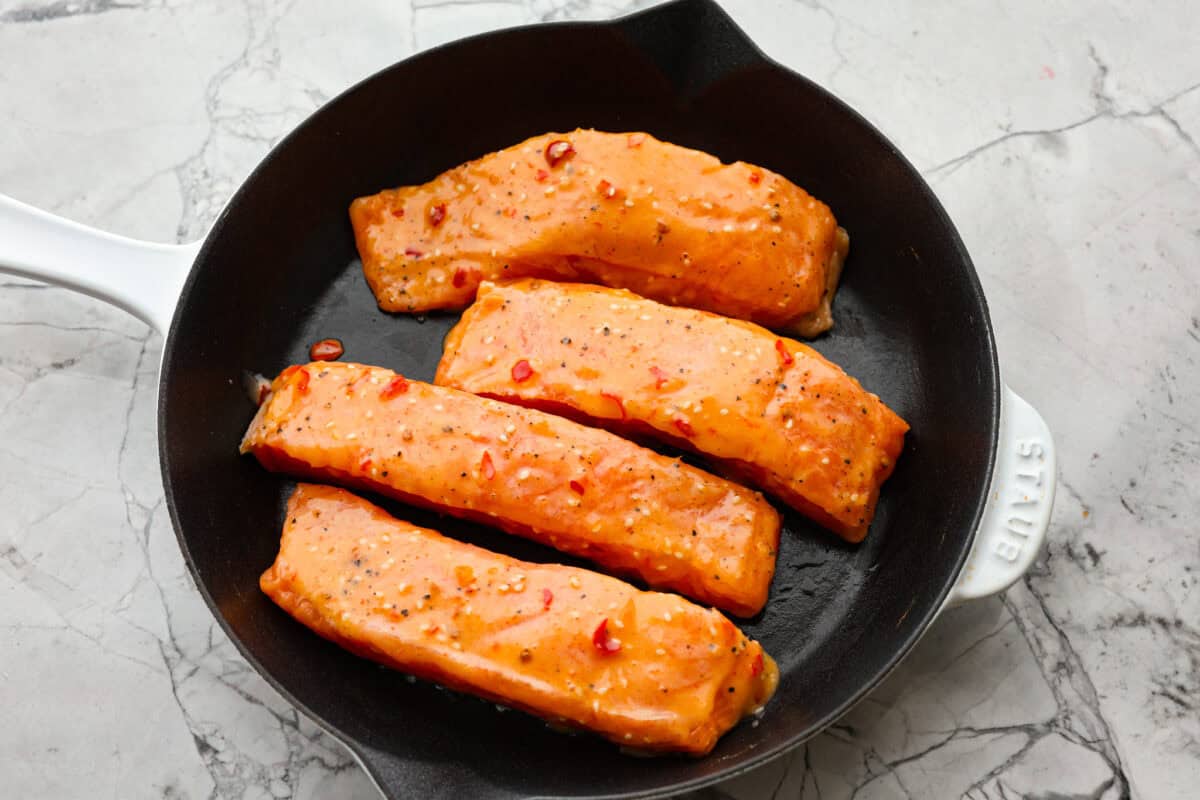 Photo of salmon fillets from above in a frying pan. 