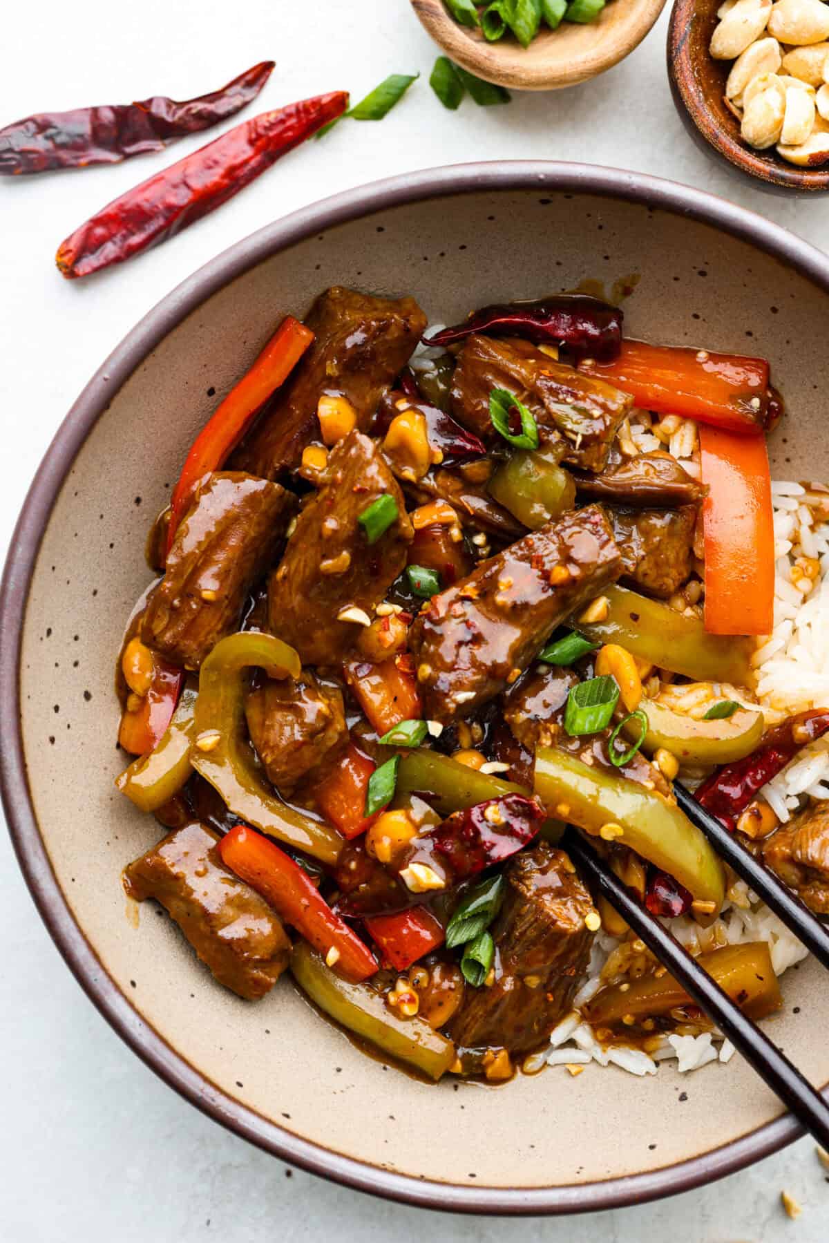 Overhead shot of plated Kung Pao beef with rice and chopsticks. 