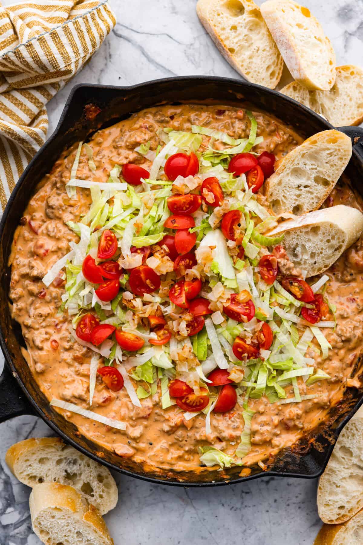 Overhead shot of cheeseburger dip topped with lettuce and tomatoes. 