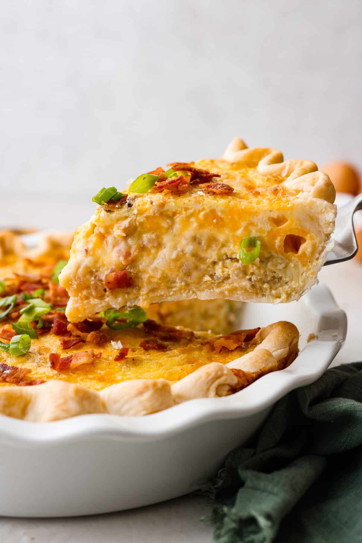 Side shot of someone taking a slice of cowboy quiche out of the pan. 