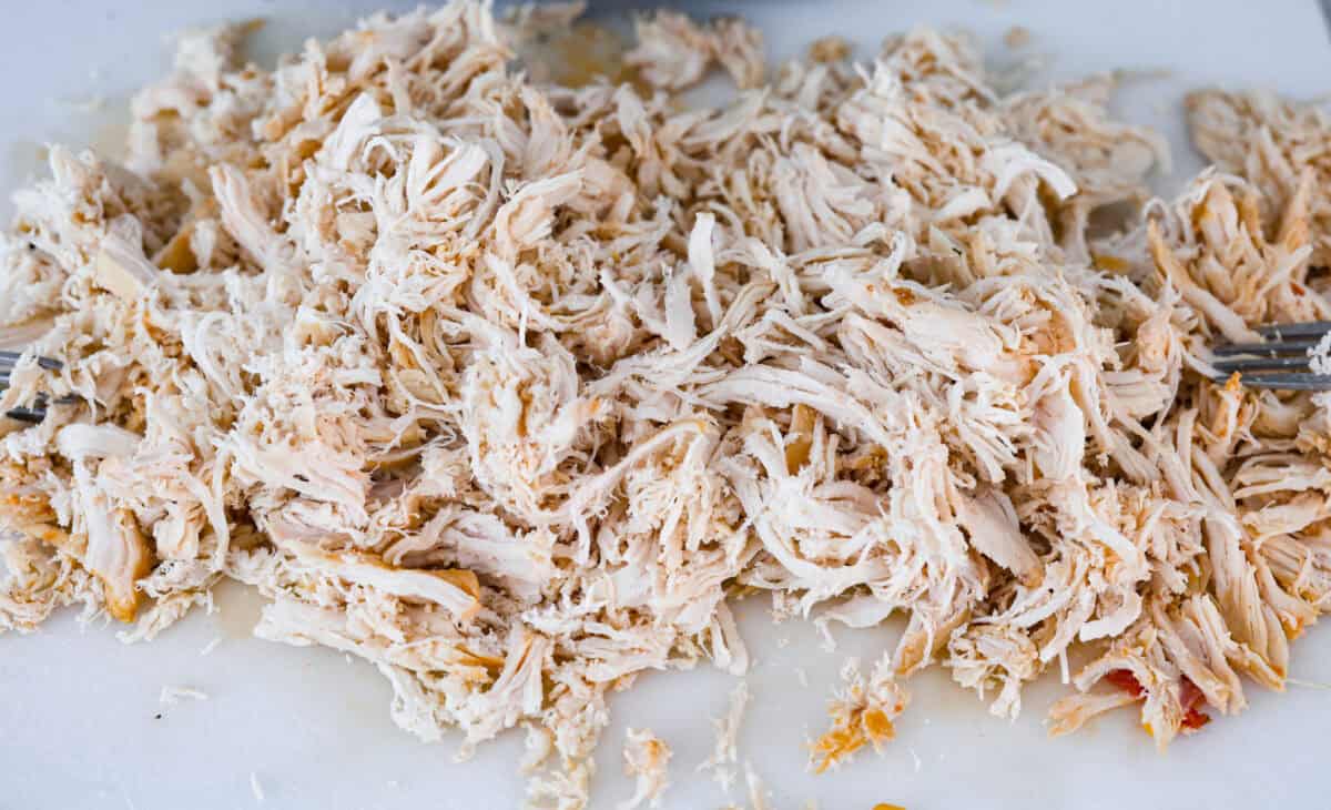 Angle shot of shredded chicken on cutting board.