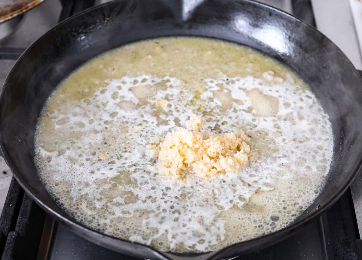 Angle shot of chicken broth and white wine mixture with garlic added. 