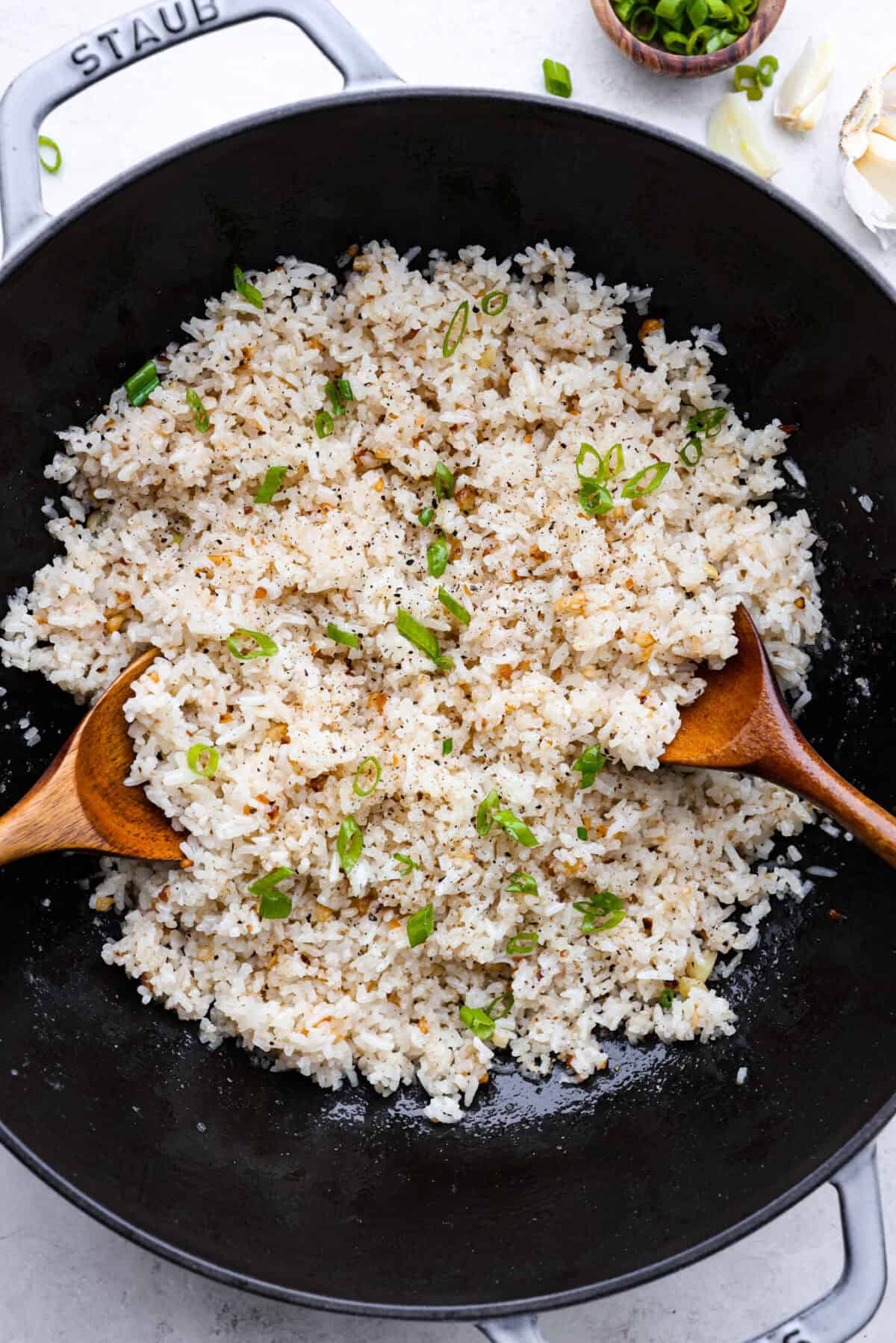 Overhead shot of garlic fried rice in a walk with two wooden spoons. 