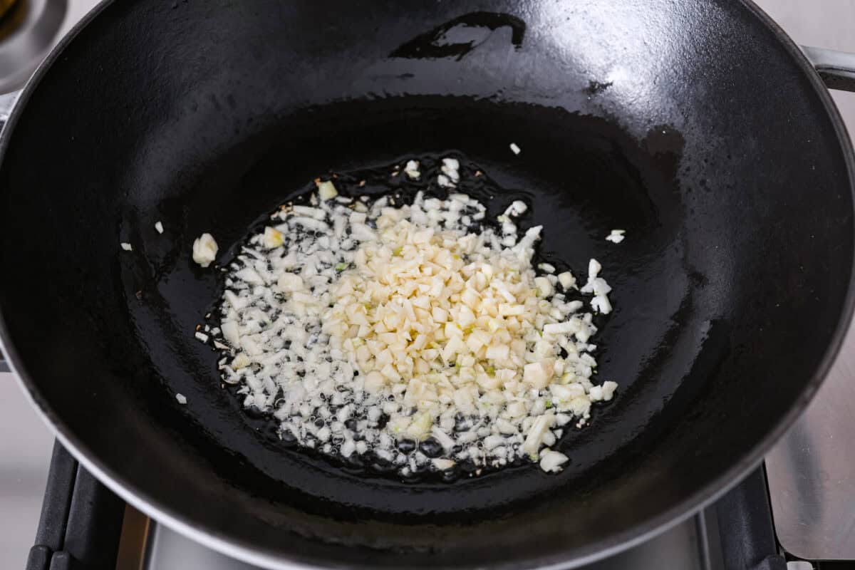 Chopped garlic shot angles are added to the oil in the pan. 