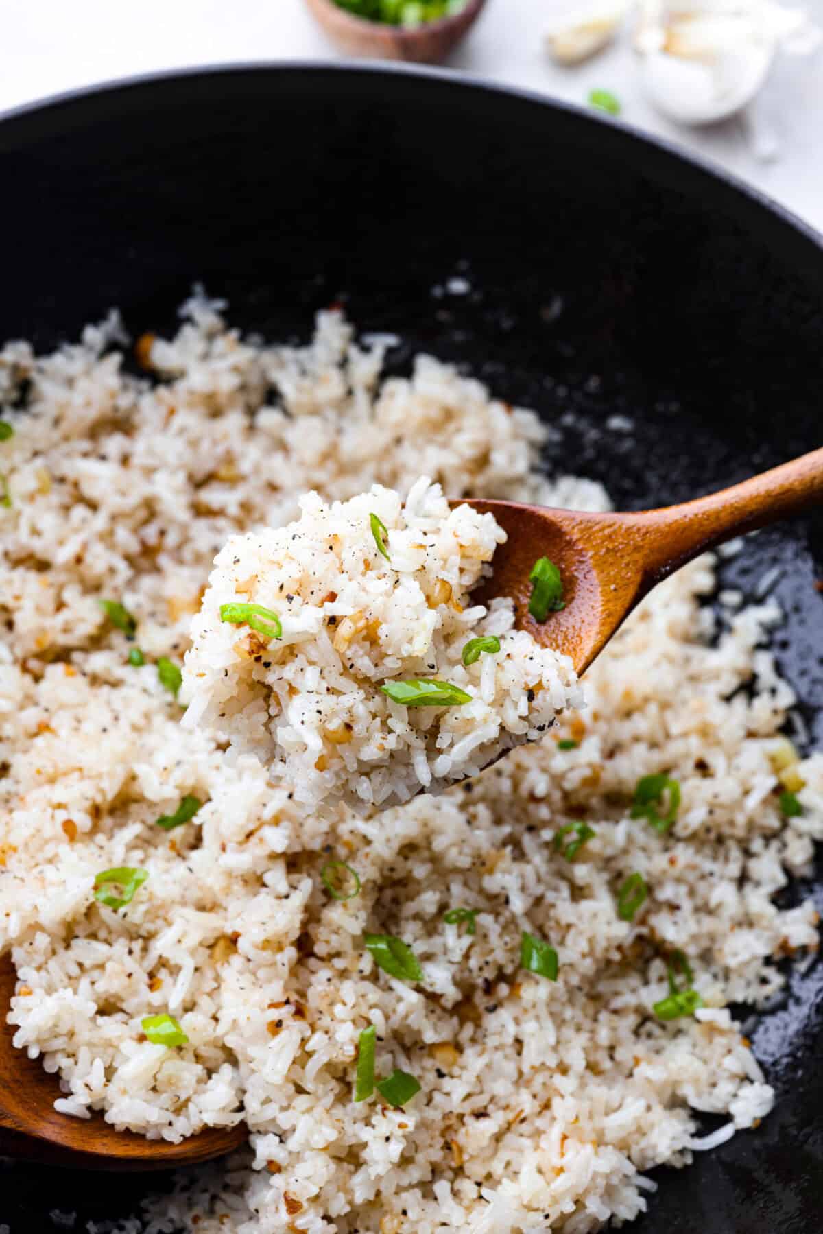 Close up photo of garlic fried rice on a wooden serving spoon. 