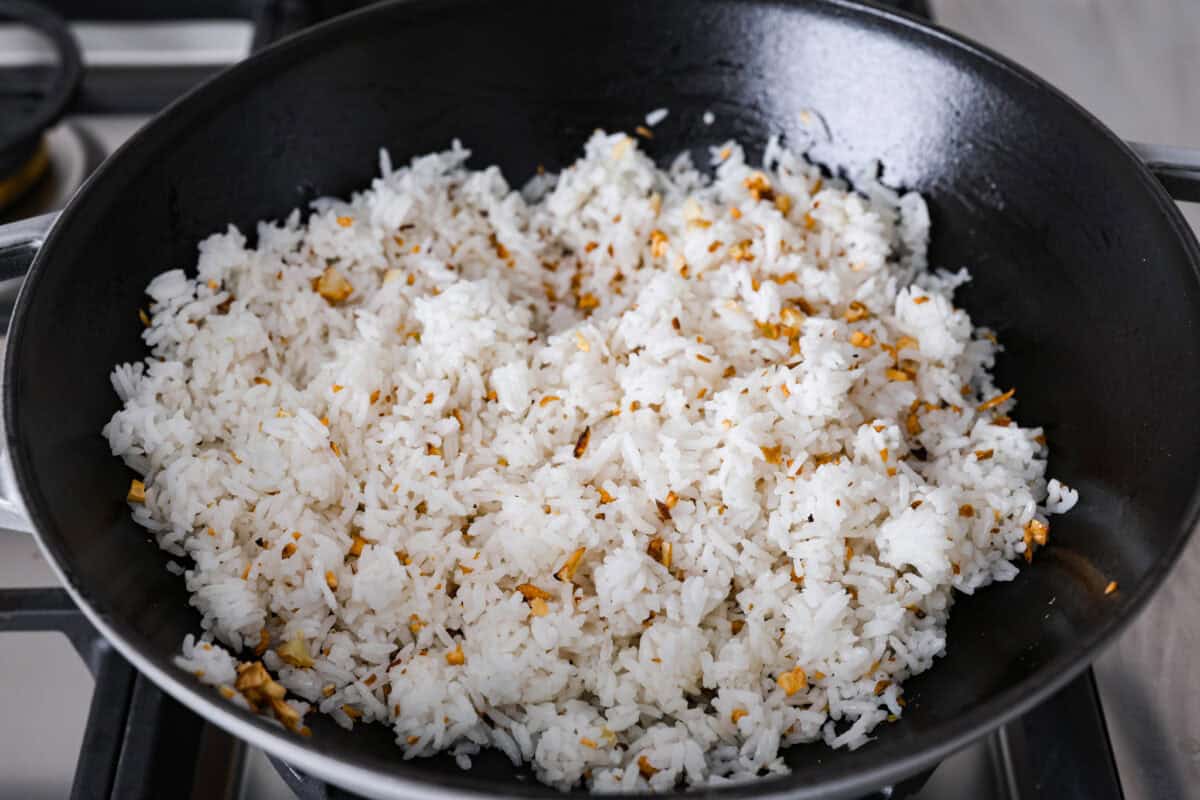 Corner shots of rice are added to the wok. 