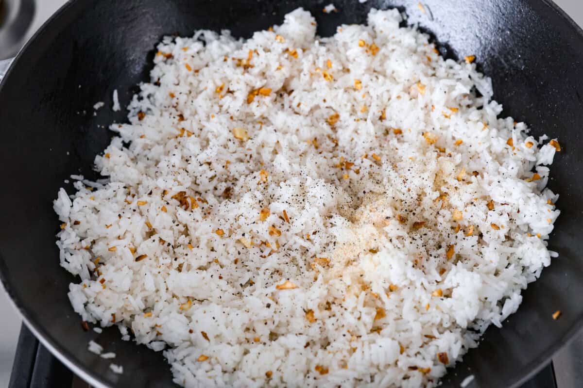 Additional spices are added to the rice in the wok. 