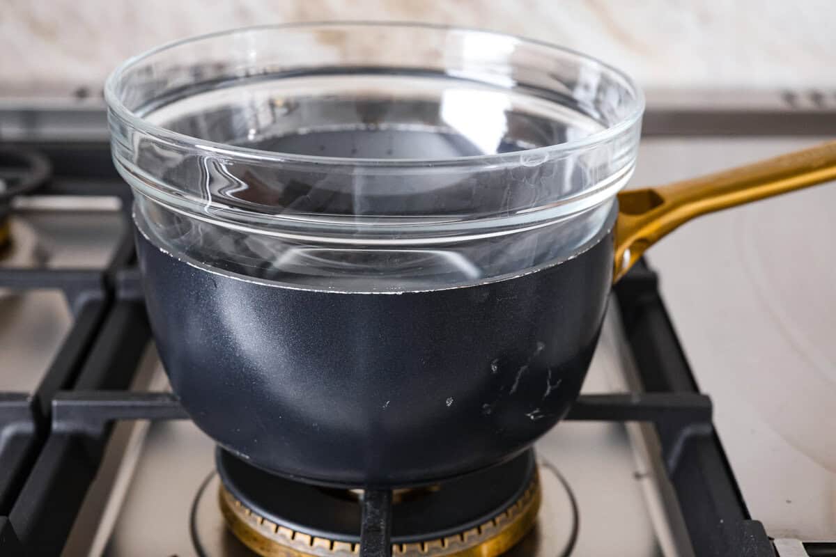 Learn how to temper chocolate for all your chocolate dipping and candy-making needs! Tempering chocolate can be intimidating but my how-to guide will help you every step of the way. Second photo of a glass bowl placed on top of the pot of water.