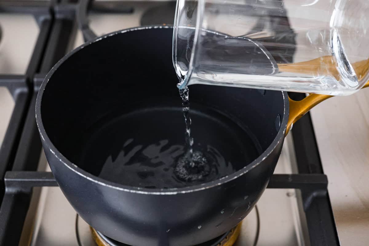 Learn how to temper chocolate for all your chocolate dipping and candy-making needs! Tempering chocolate can be intimidating but my how-to guide will help you every step of the way. First photo of water adding to a pot to make a double boiler.