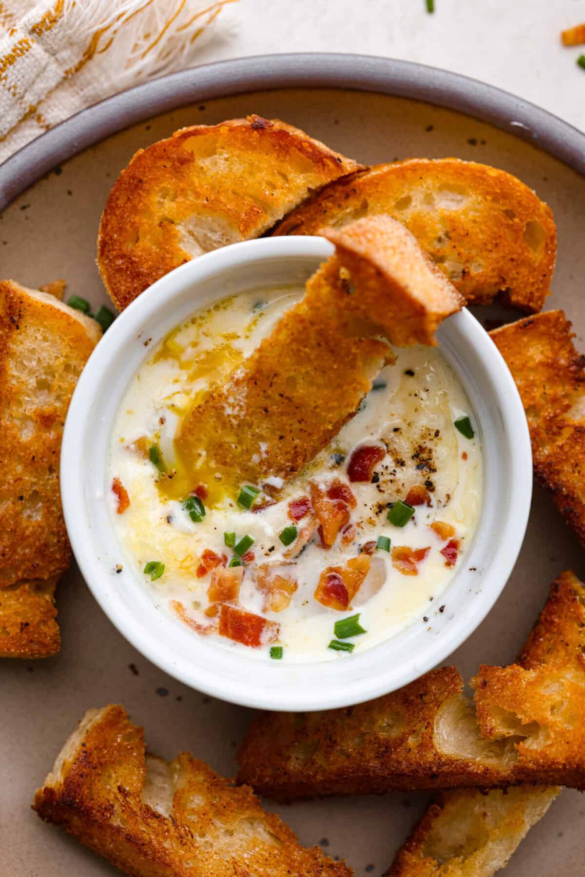 Top shot of shirred eggs in ramekins surrounded by crostini.