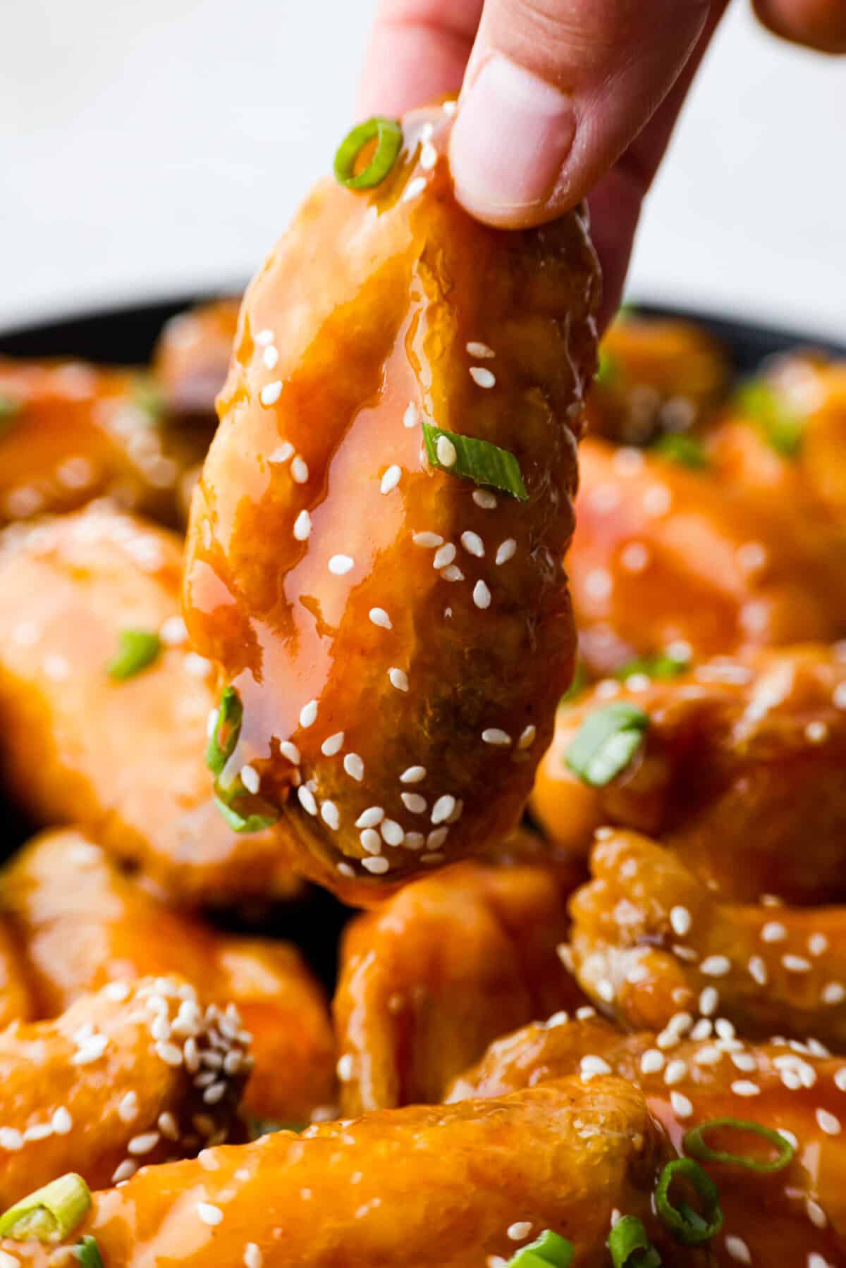 Close up shot of sweet and sour wing being lifted off the platter. 